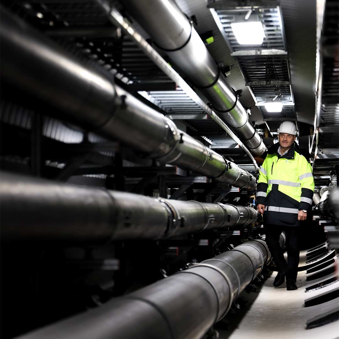 A person in a safety vest and hardhat standing in a factory