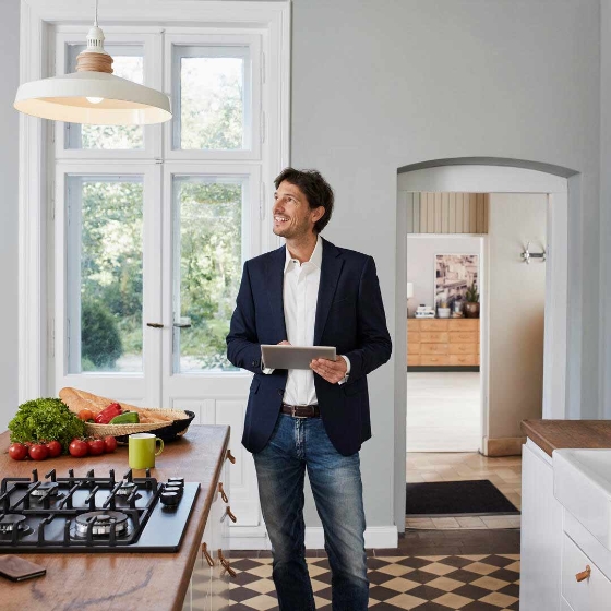 Man using tablet in kitchen looking at ceiling lamp