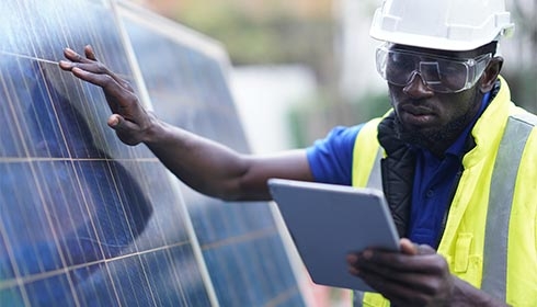 A person in safety gear pointing at a tablet