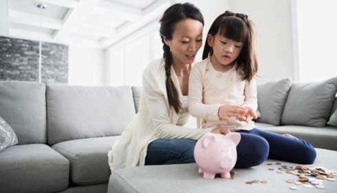 Mother and daughter counting coins from piggy bank