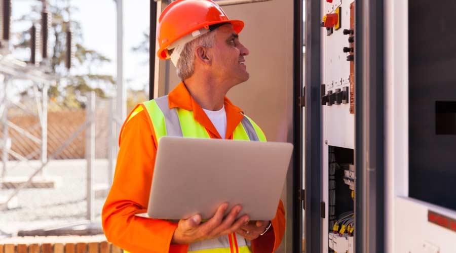 Experienced senior electrician working on a transformer in substation