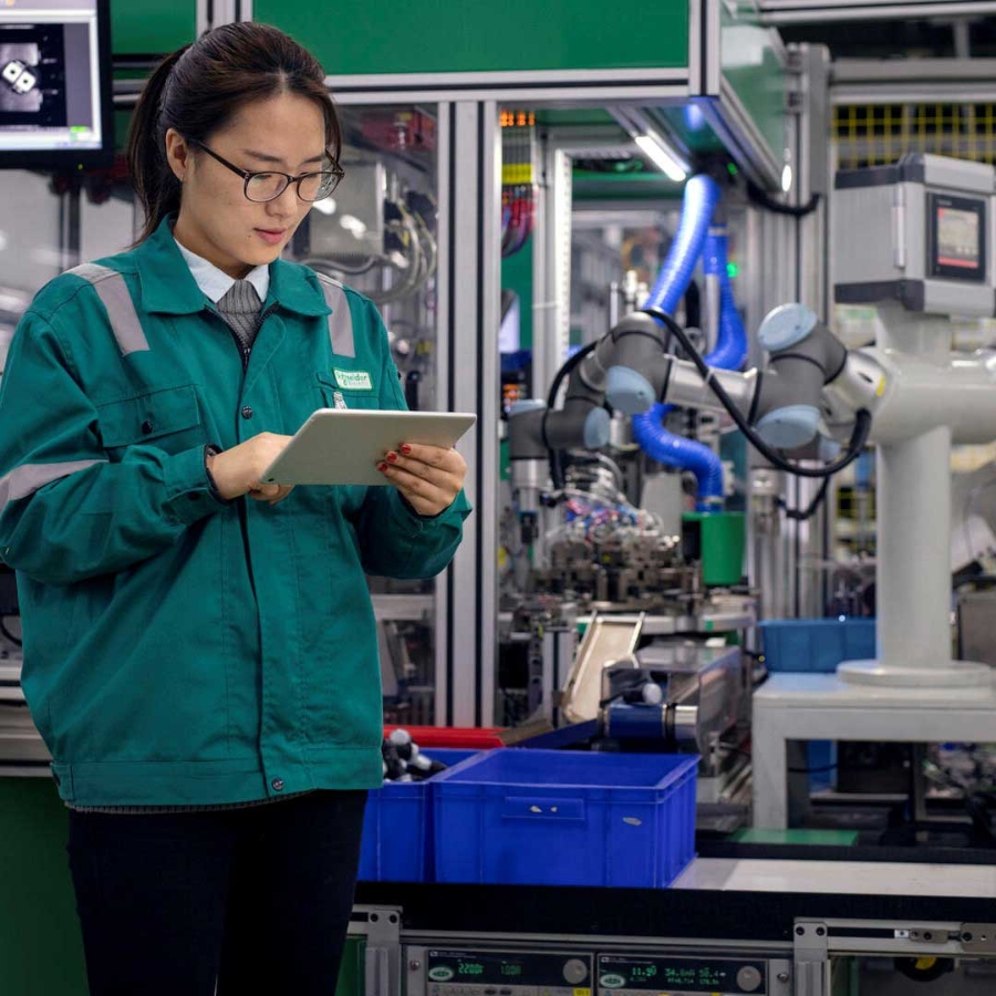 An engineer inspecting a robot arm with a digital tablet in her hand