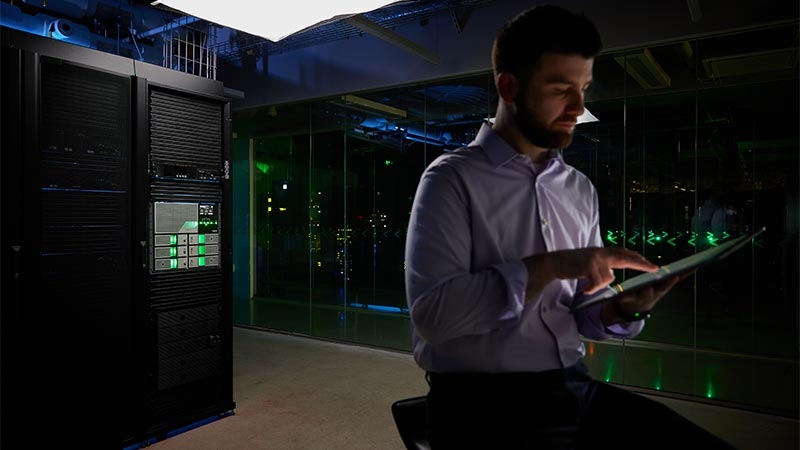 A person holding a tablet in a server room