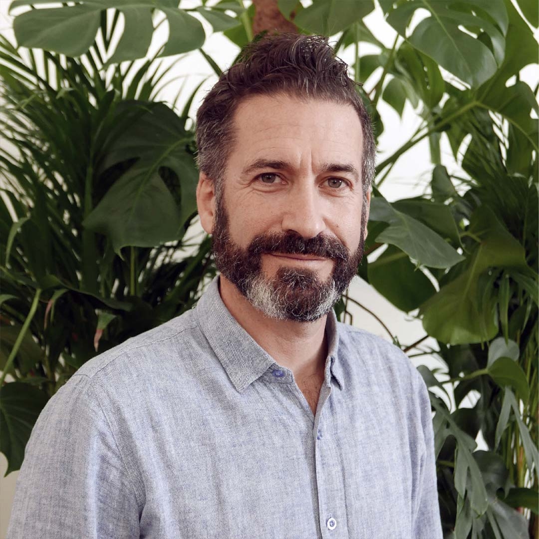 man with beard smiling in front of plants