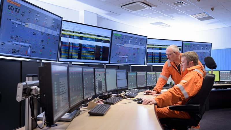 Workers monitoring the control room with digital equipment indicating energy production and distribution