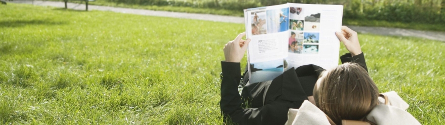 a person lying in the grass and reading