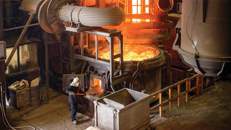 Steel worker working at an open electric steel furnace in an industrial foundry