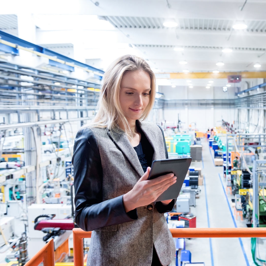 Businesswoman holding a digital tablet laying on the railing in a factory