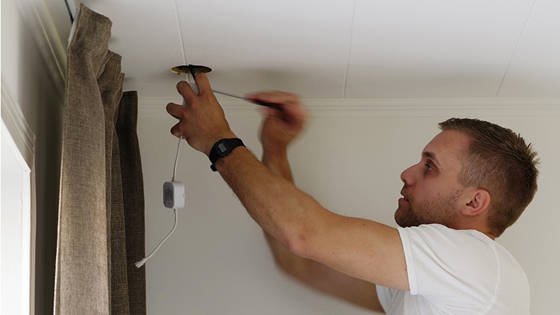 Electrician installing downlight in ceiling