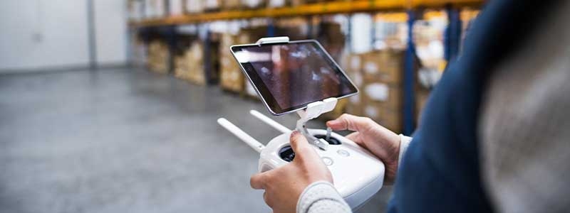Man with tablet and drone controller in a warehouse