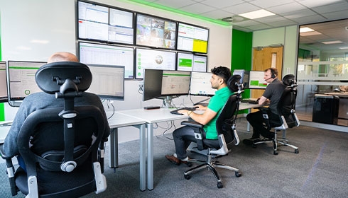 A group of men sitting at desks in a room with computers