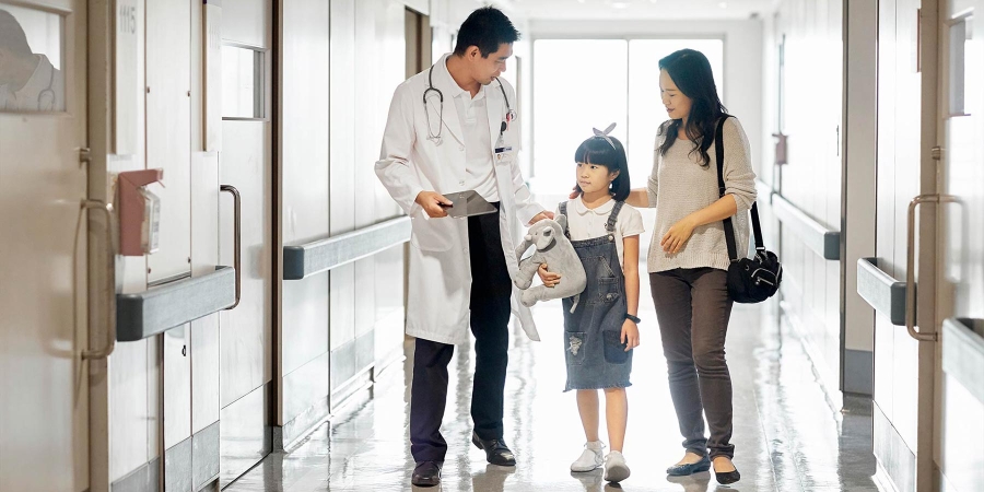 a doctor walking with a kid and a woman