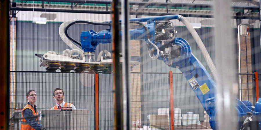 two men operating a robotic arm in a factory