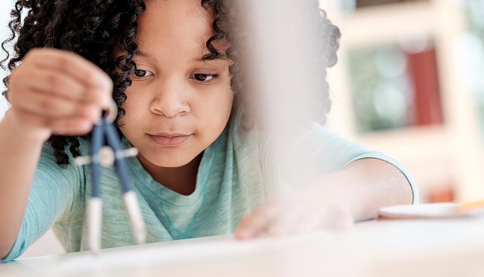 American girl using compass in science classroom