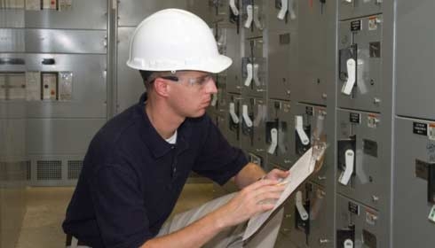 An employee checking on the electrical machine and writing down what he notices, energy management, power management, field service