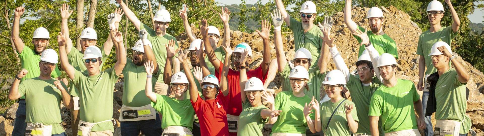 Group of volunteers of Habitat for Humanity raising their hands