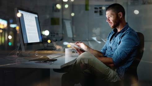 businessman using a computer and digital tablet during a late night at the office