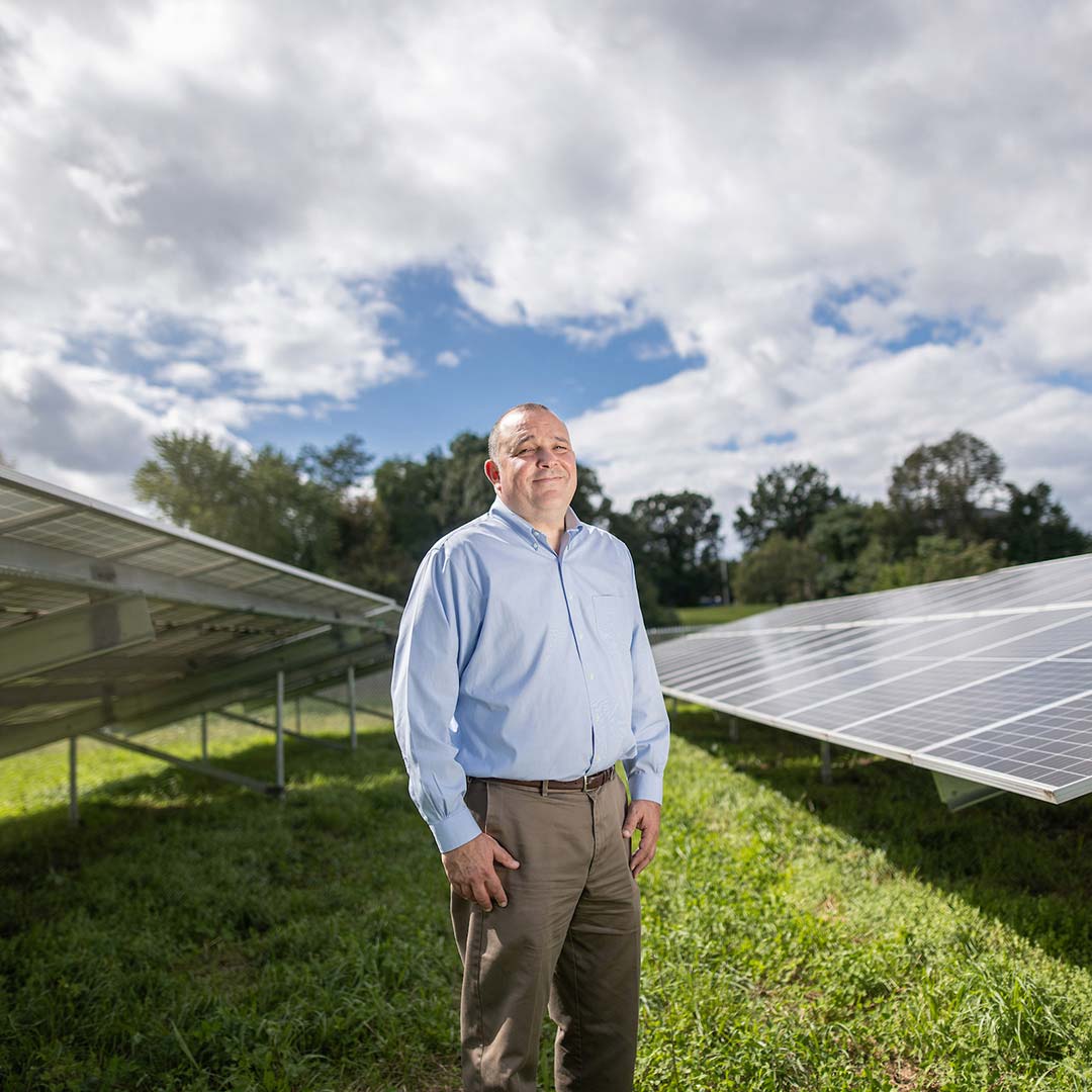 Steve Bern posing for a picture in front of solar panels