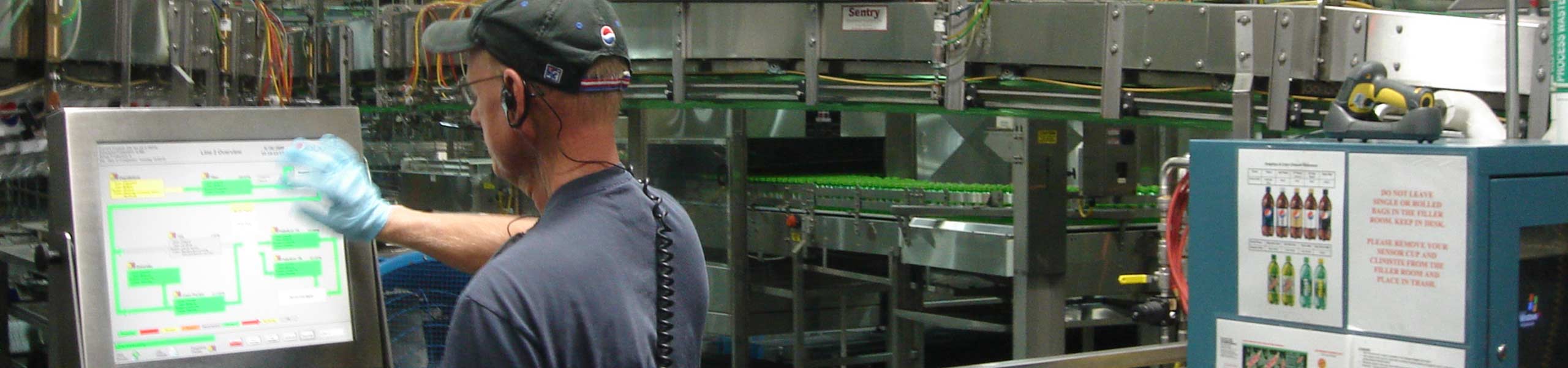 Male worker on the computer on the manufacturing floor using facility management software.