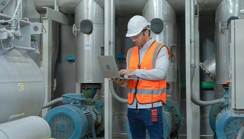 A person in a hard hat and safety vest using a computer
