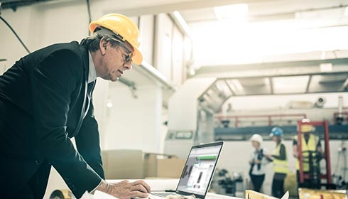 A person wearing a hard hat and looking at a computer
