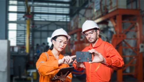 A person and person wearing hard hats and holding a tablet
