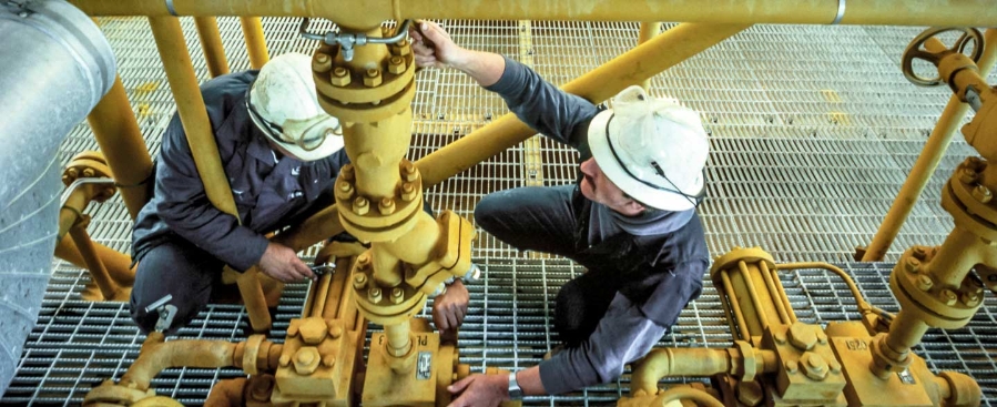 Workers inspecting oil and gas piping, process automation.