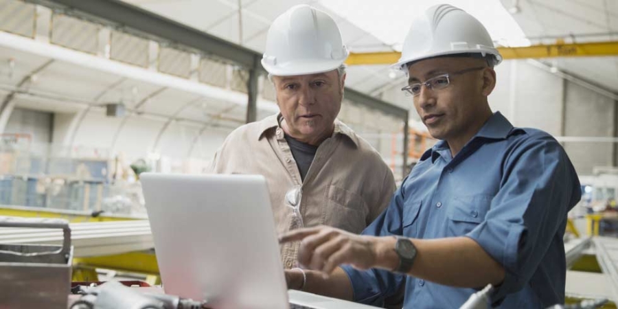 Workers at laptop in manufacturing plant