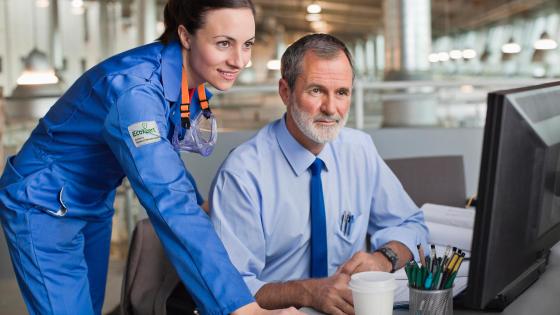 Businessman and engineer using computer in factory, facility management software, sustainability consulting.