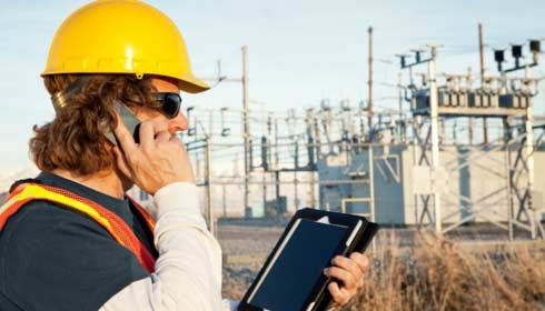Power line technician using phone and tablet, sustainability reporting, internet of things.