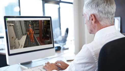 Businessman at computer using a 3D animation type of software, facility management software.