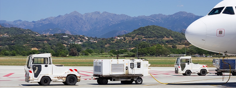 Airport vehicles towing white modern aircraft on the parking lot