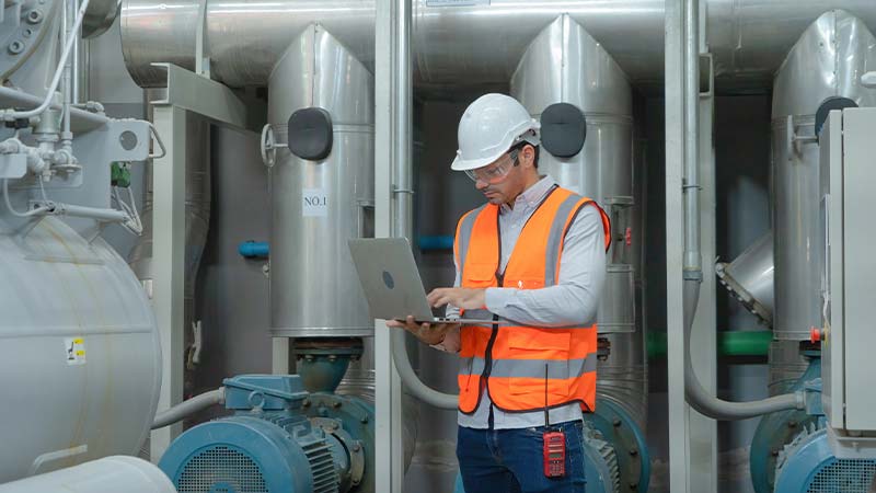 A person in a hard hat and safety vest using a computer
