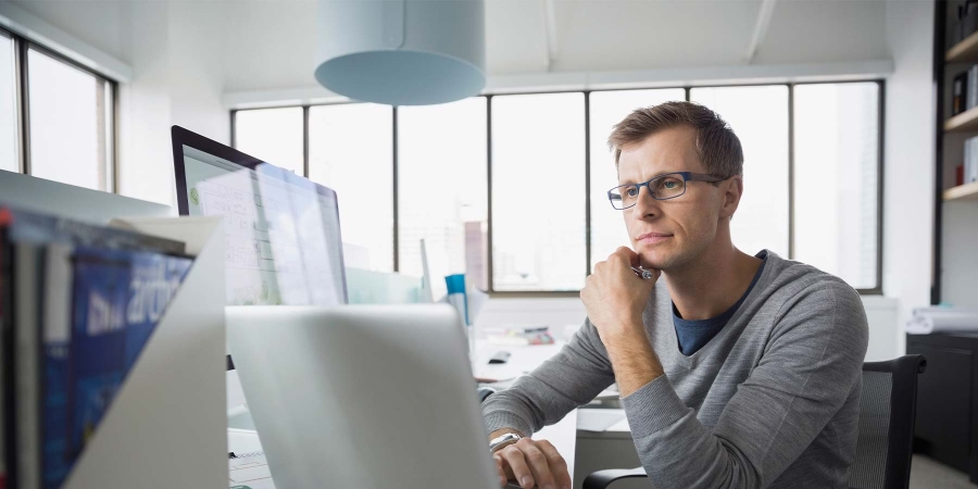 A person sitting at a desk with his hand on his chin