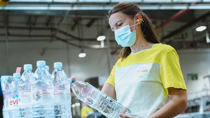 A person wearing a face mask holding a bottle of water