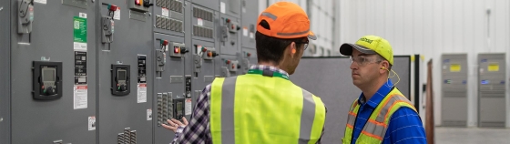 A person wearing a safety vest and orange hat