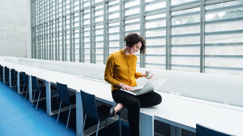 Young student or businesswoman sitting on desk
