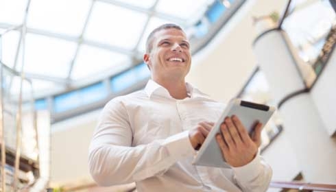 Businessman with tablet computer in hands, blurred background, modern business building