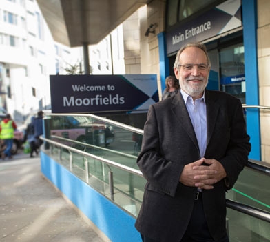 A man standing in front of Welcome to Moorfields Eye Hospital