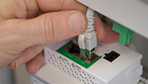 A hand connecting an ethernet cable to a smart panel